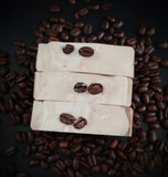 Brown swirled artisan soap made with brewed coffee topped with real coffee beans