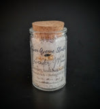 White bath salts with lavender and jasmine buds pictured in a corked jar