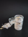 White bath salts with lavender and jasmine buds pictured in a corked jar