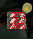 Bars of soap with vampire fangs and blood splatter on top with a dark rose and candle on a black background