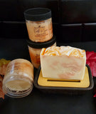 Light orange sugar scrub in clear PET jar with black lid. Paired with the matching soap. Orange swirled soap sitting on a soap dish.