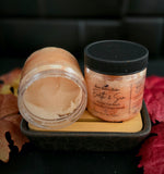 Light orange sugar scrub in clear PET jar with black lid.
