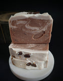 Brown swirled artisan soap made with brewed coffee topped with real coffee beans