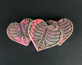 Heart shaped soaps with rib cage design in black and pink colors against a dark background