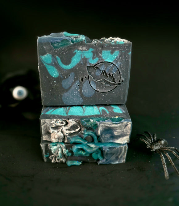 Three bars of black and blue soap stacked on a dark background