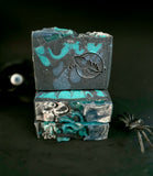 Three bars of black and blue soap stacked on a dark background
