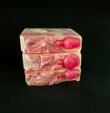 Three stacked soap bars with pink and white swirls on a black background