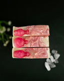 Three bars of soap with pink and white swirl design on a dark background