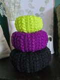 Three crocheted pumpkins in green, purple, black sparkle.