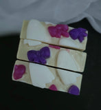 Three rectangular bars of handmade soap stacked vertically. The soap has a creamy off-white base with pink and purple bow shapes and white ghosts.