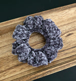 Crochet hair tie in grey on a wooden tray