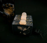 A dark, gothic-themed soap bar with a soap crystal ball on top, featuring a dark charcoal and cream marbled pattern set against a dark background with a small black spider prop.