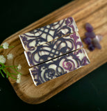 Decorative soap bars with purple and white design on a wooden board.