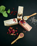 Three soap bars with natural ingredients on a dark surface