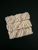 Three bars of soap with knit texture on a black background