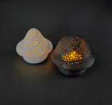 Two decorative lace-like mushroom lamps with intricate designs on a dark background, shown in point top (white) and round top (black)