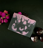 decorative soap bar in black and purple with flame design and purple flowers topped with a garnet on a dark background
