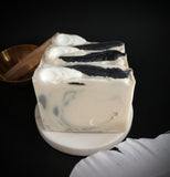 Cream and grey swirled soap with white soap raven skull and  black soap bird feather on top and a touch of eco glitter.