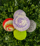 Colorful crocheted balls on a green leafy background