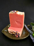 Pink soap bar with floral toppings on a dark background