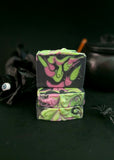 Black soap bar with bright green and purple swirls on a black background.