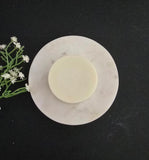 Light cream colored conditioner bar pictured on a black background.