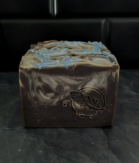 Soap bar in dark purple and silver accents on a black background.