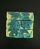 Three green soap bars with leaf patterns on a black background