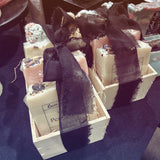 Decorative soap bars with black ribbons in a wooden box on a dark surface.