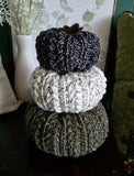 Three crocheted pumpkins in black, white and green with a faux leather leaf.