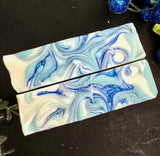 Two bars of soap with blue and white marbled pattern on a dark surface.