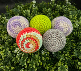 Colorful crocheted balls on a green leafy background
