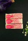 Three marbled soap bars with pink and white swirls on a dark surface.
