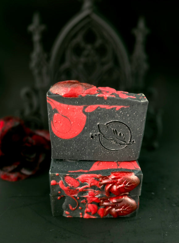 Two black soap bars with red designs stacked on a dark background