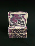 Three bars of soap with a purple and black swirled design on a black background