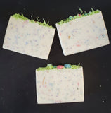 Ostara Coconut Milk Artisan Soap. White soap bar with rainbow speckles, soap grass and eggs on top.
