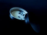 Dark magick brew solid lotion bar with coffee beans inside sitting inside a black tin