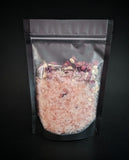 Enchanted Berry Ritual Soaking Salt with dried rose petals and jasmine buds, pictured in black bag