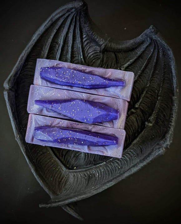 purple soap bar with fuchsia swirls and a purple soap crystals on top with holo glitter